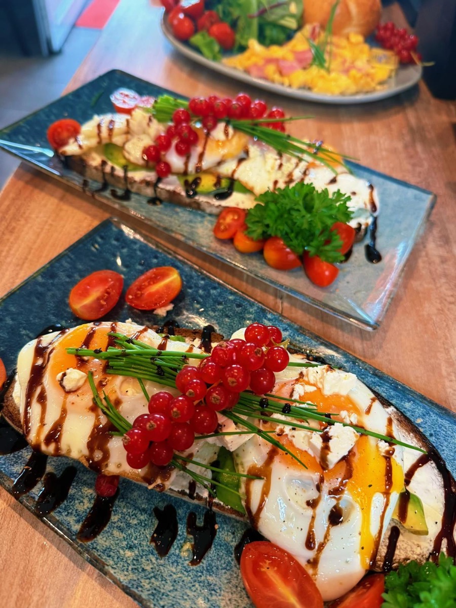 Avocado-Brot auf dunklem Bauernbrot mit Spiegelei, Feta-Käse, Johannisbeeren und Balsamico
