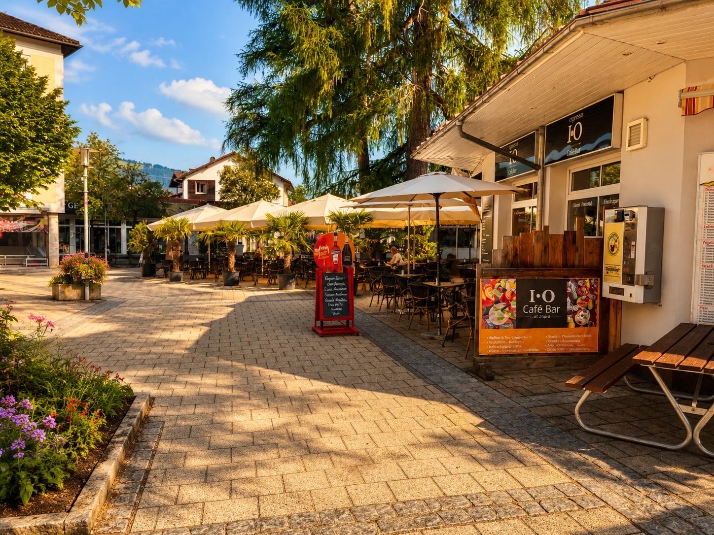 Terrasse der I·O Café Bar mit Palmen und Sonnenschirmen in der Sonthofener Innenstadt
